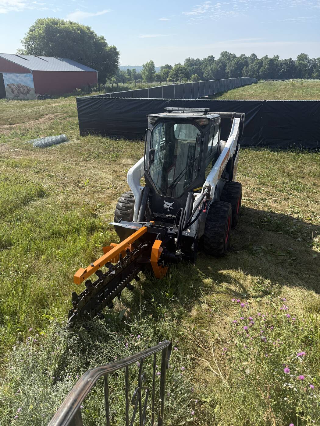 Bobcat skid steer with trencher attachment ready to dig
