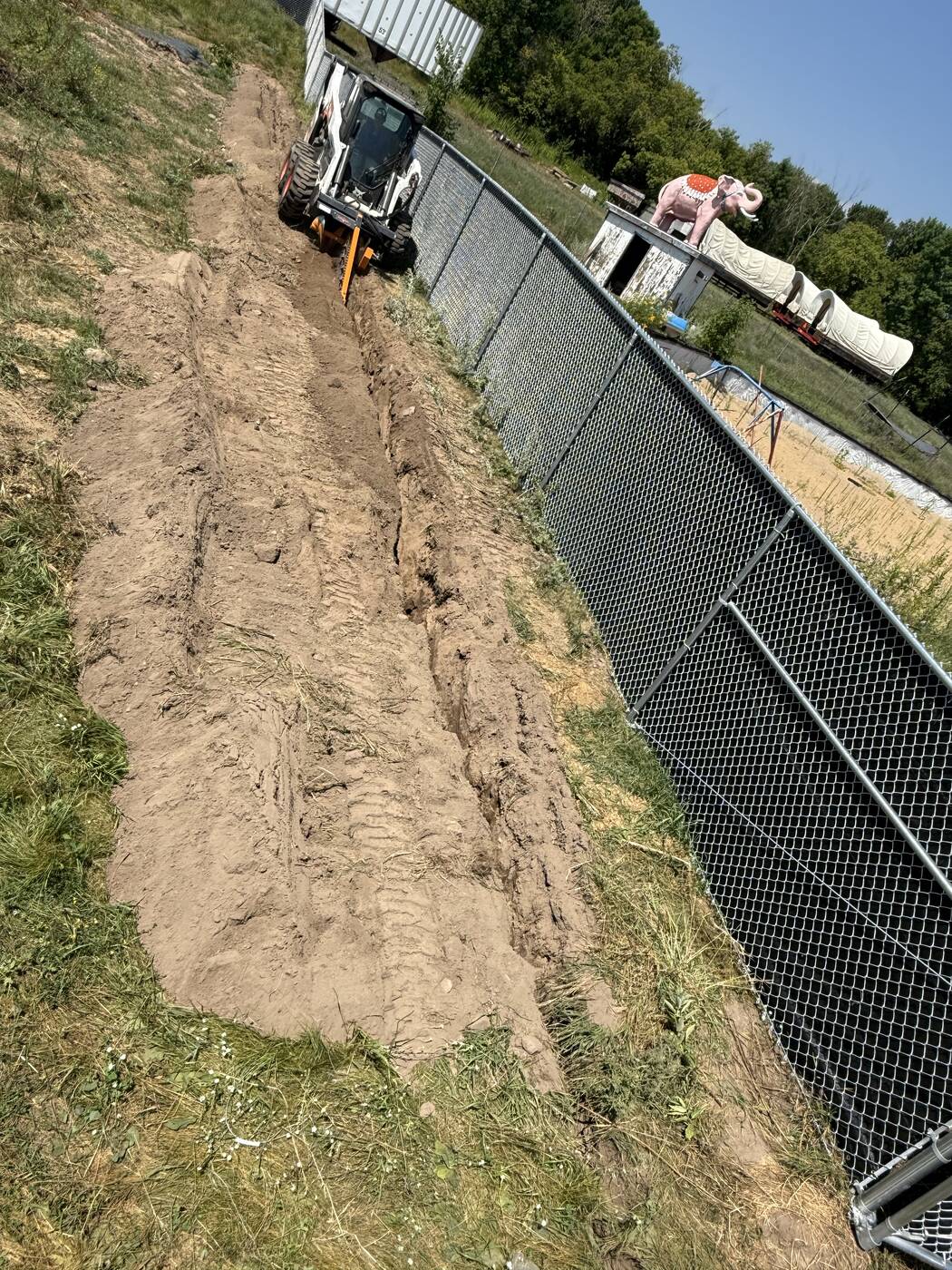 Backfilled trench line blended along the fence
