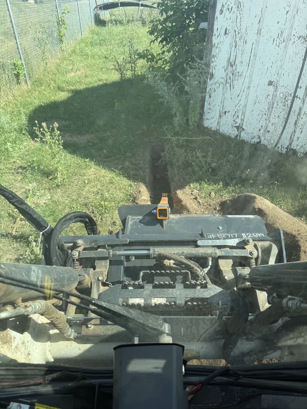 Cab view trenching a run alongside a building