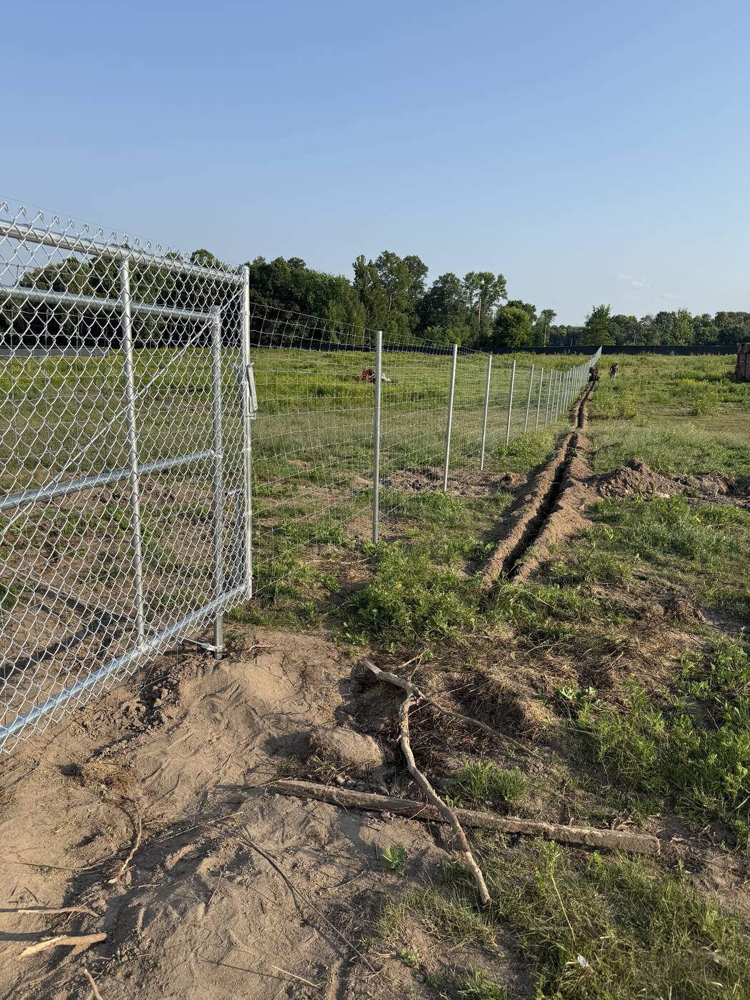 Backfilled trench line through a fence gate opening